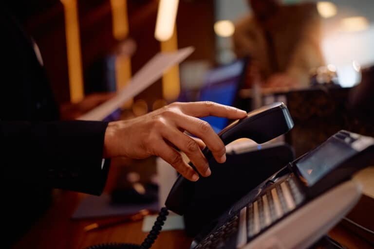 Close up of receptionist answering a phone call while working in a hotel