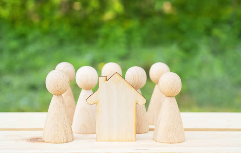 Family concept. Wooden house and many little men on a wooden table. Property division
