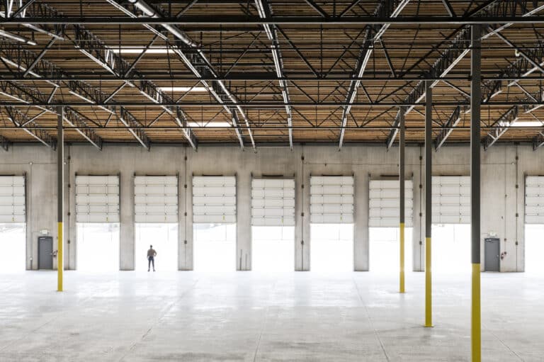 Owner silhouetted and standing in a loading dock door for a new empty warehouse